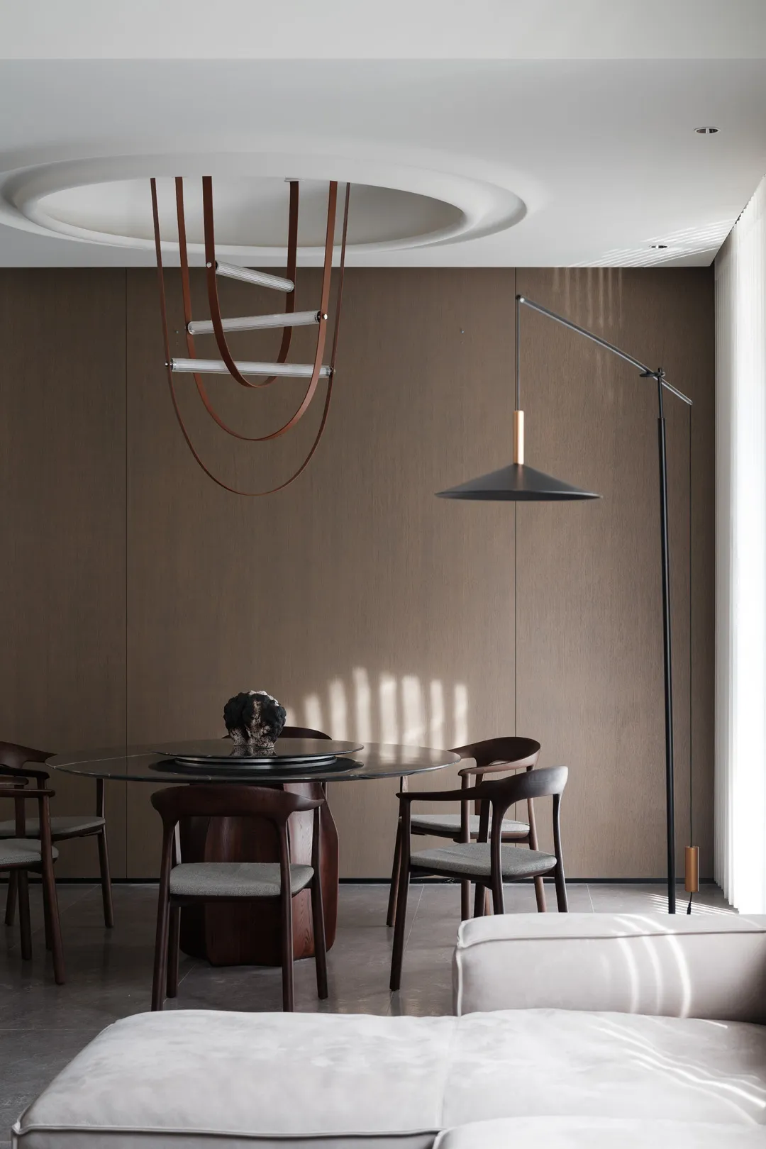 A modern dining room featuring a combination of metal and leather accents on the table, chairs, and lighting fixtures.