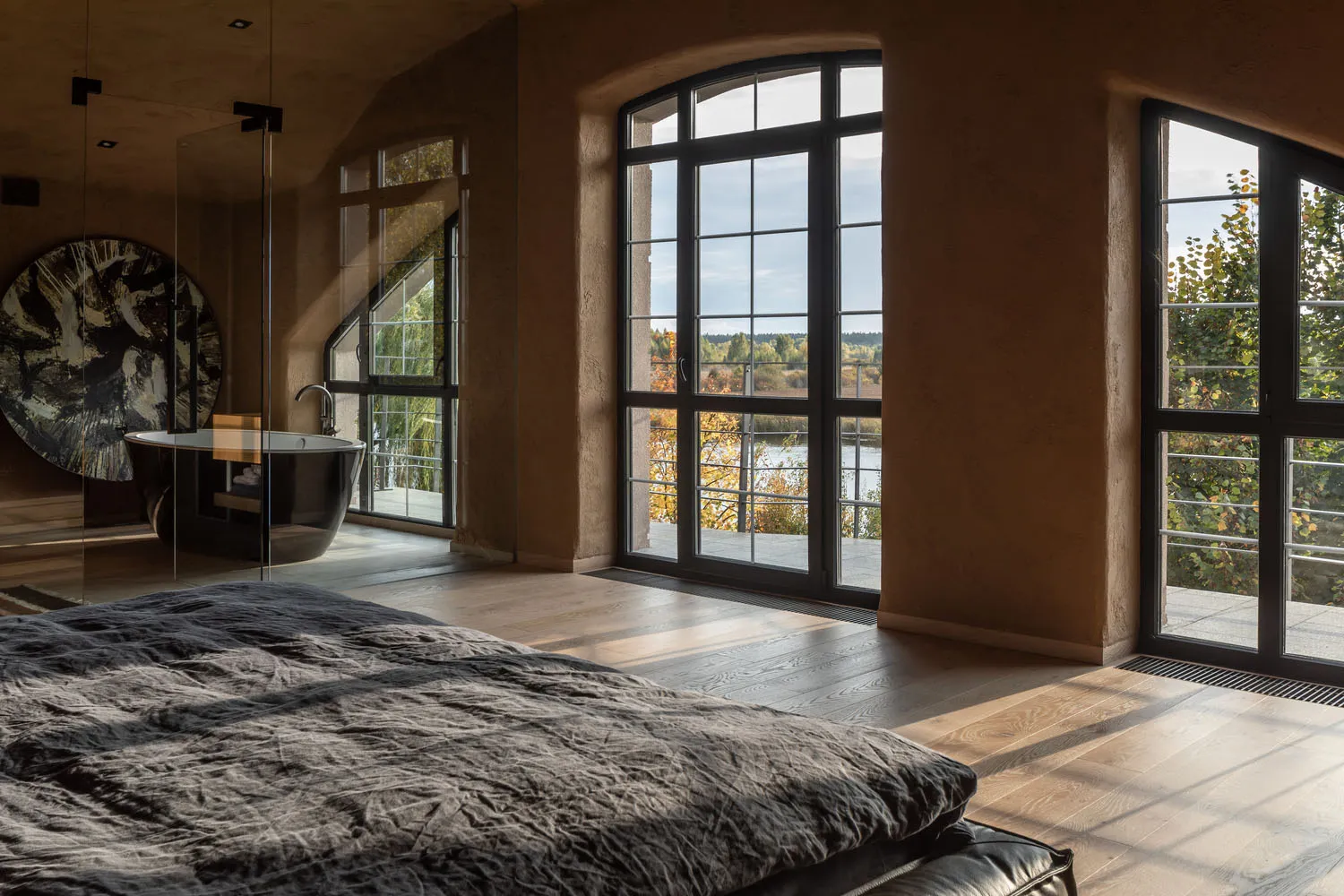 Luxurious, dark-themed bedroom interior with large windows overlooking nature.