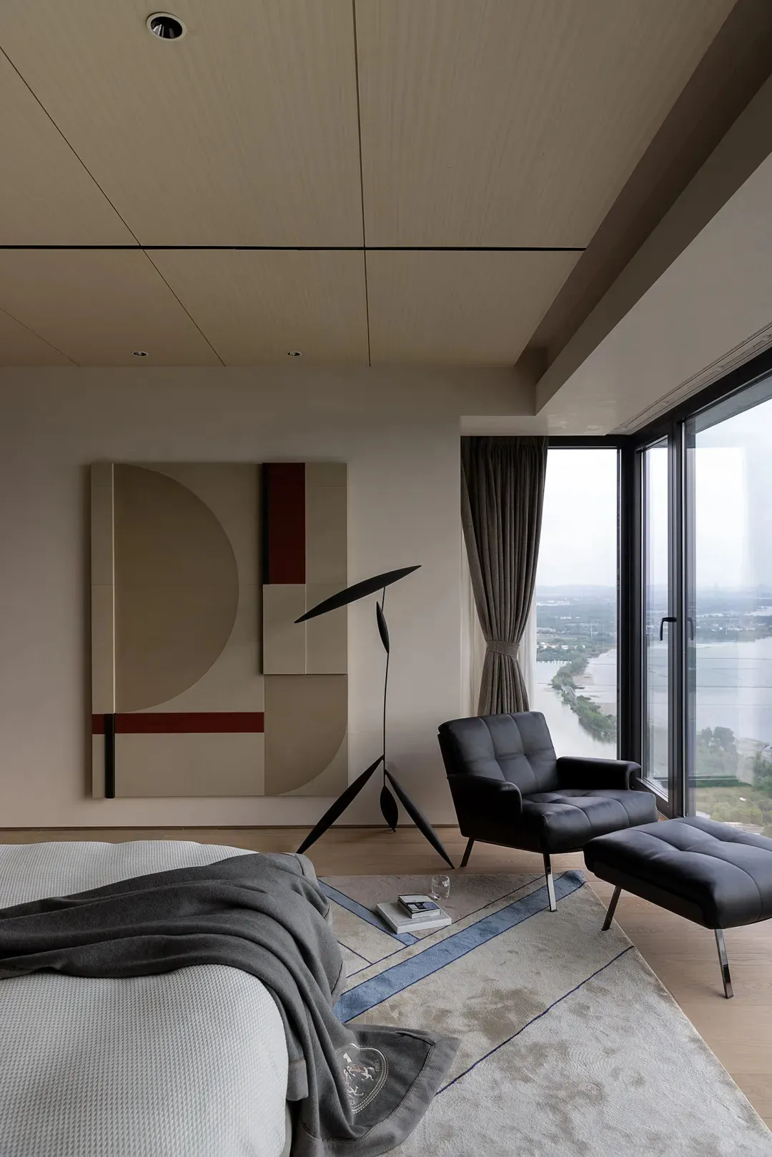 Contemporary minimalist bedroom featuring a leather armchair, a large artwork, and a floor lamp.
