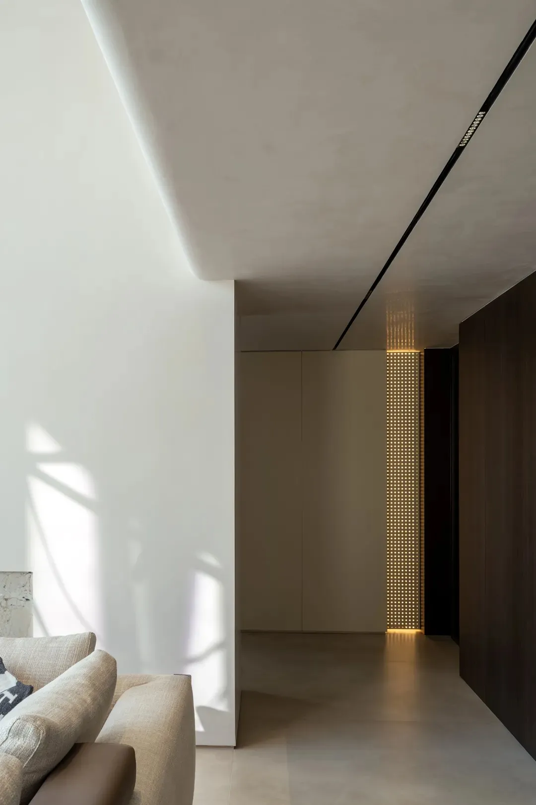 Modern residential corridor featuring concrete flooring and lighting details.