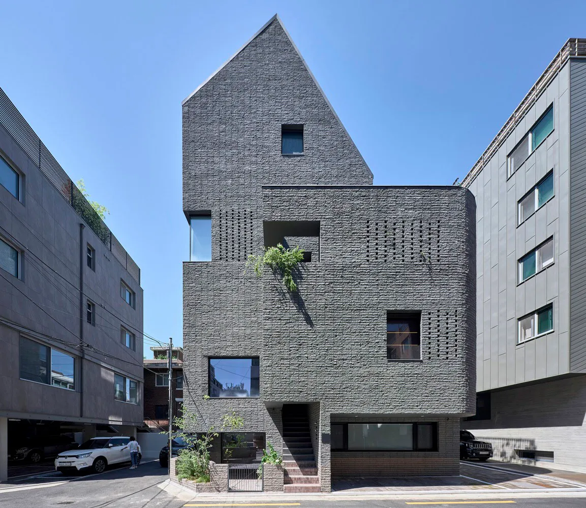 一座現代磚造建築,擁有獨特的角度設計,位於都市環境中。