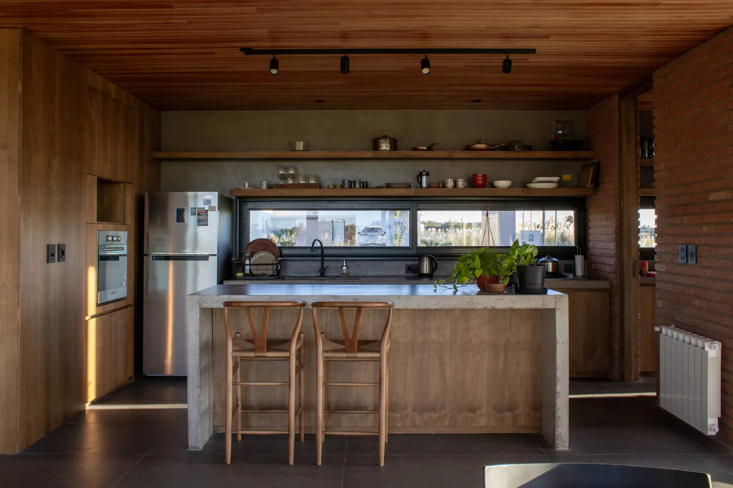 A modern kitchen with a concrete countertop and wooden stools.