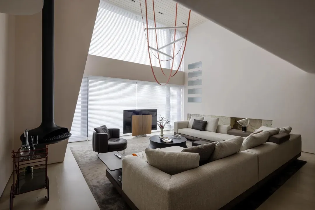 A modern living room with a concrete fireplace, a large U-shaped sofa, and a unique lighting fixture.