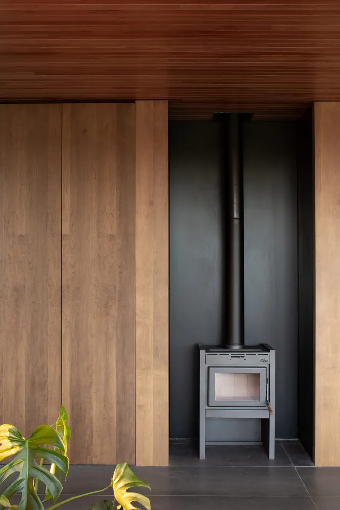 A minimalist interior with a wooden wall and a modern fireplace.