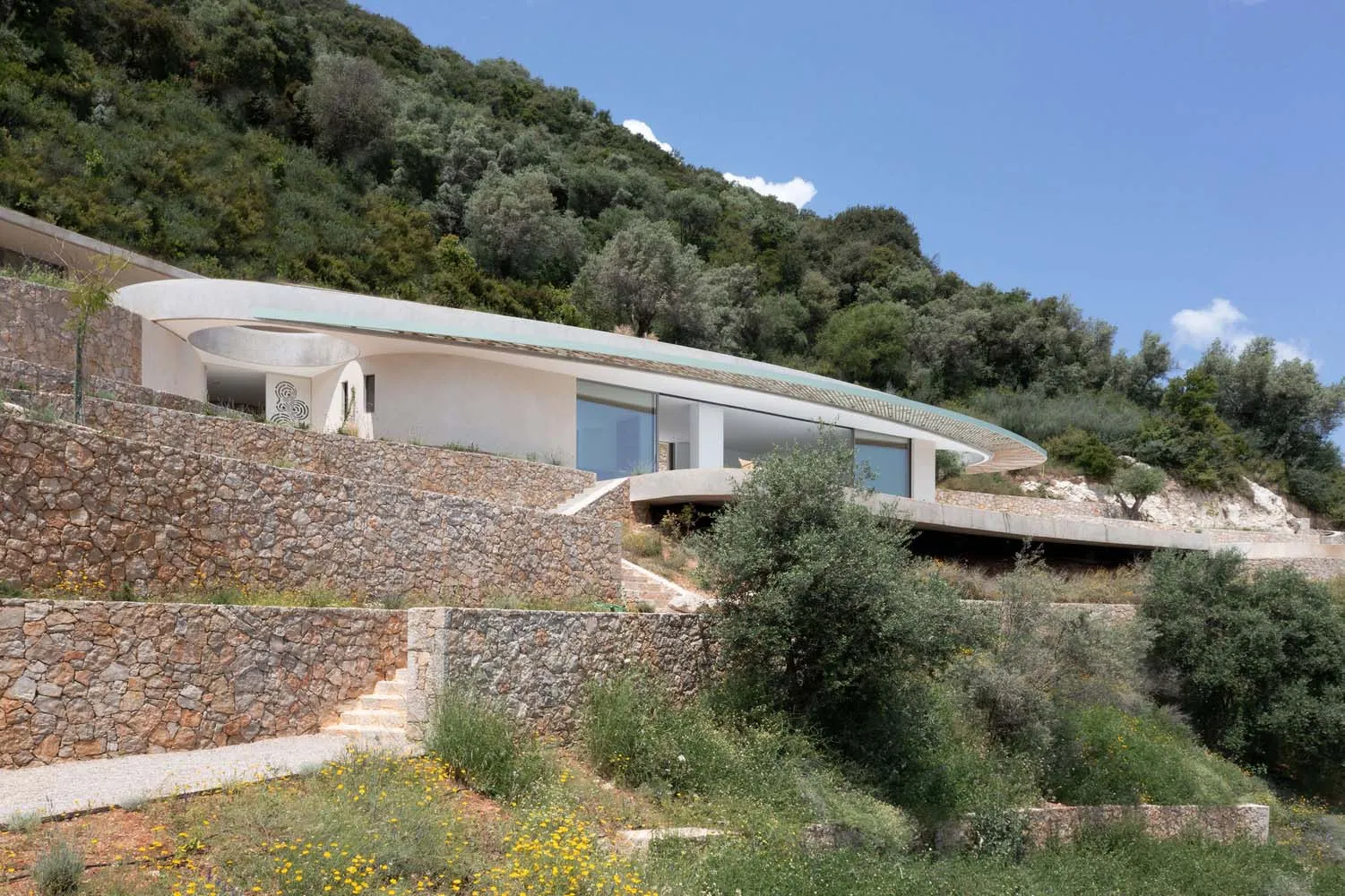Modern residential house with concrete exterior on a grassy hillside