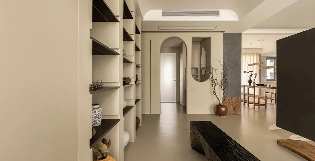 Minimalist residential interior featuring a concrete floor and white bookshelf with decorative items.