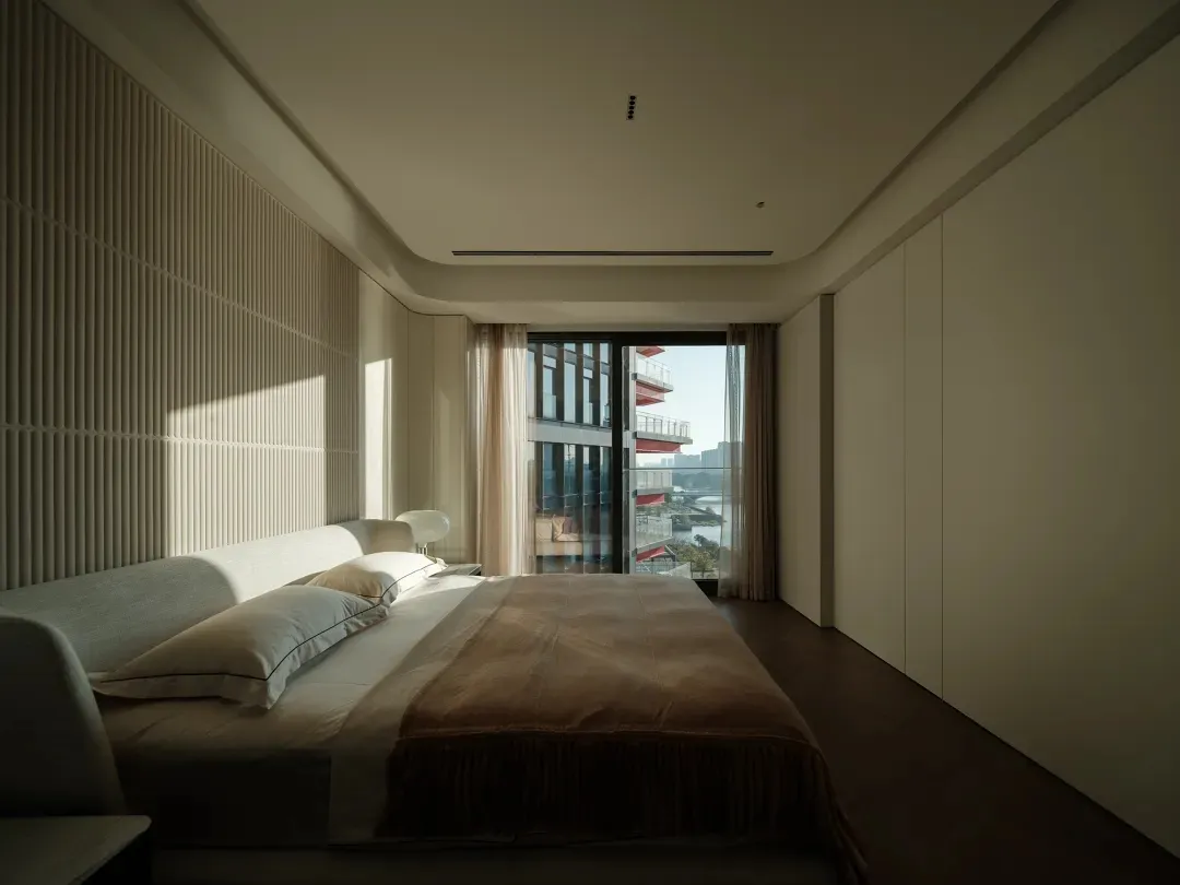 Modern minimalist bedroom featuring a bed with wooden frame, glass window, and fabric bedding.