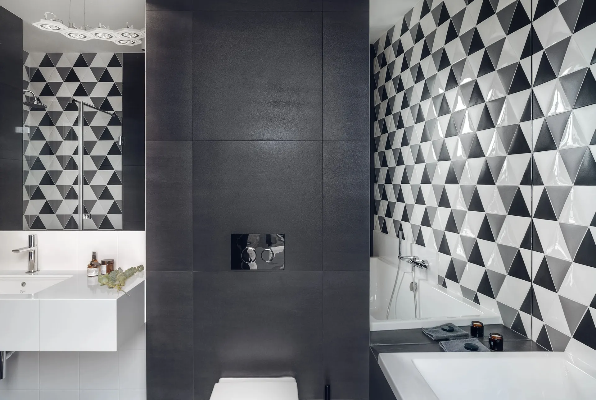 A modern bathroom featuring a black and white patterned tile wall, a walk-in shower, a white bathtub, and a floating white va