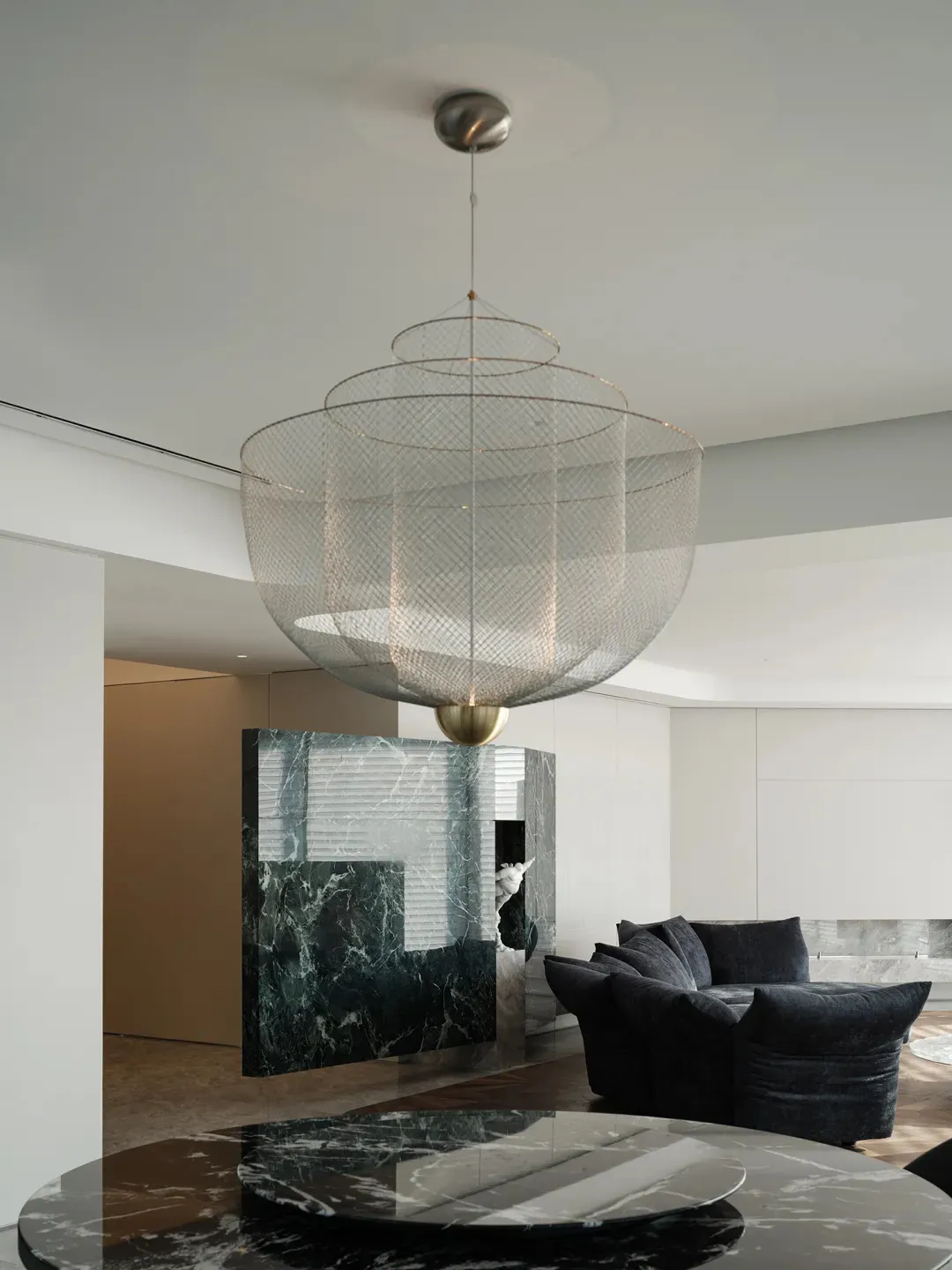 A modern living room with a metal netting chandelier hanging from the ceiling.