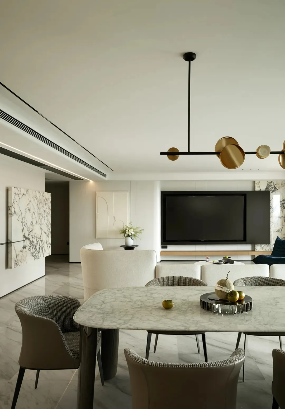 A minimalist living and dining room with marble accents and modern furniture.