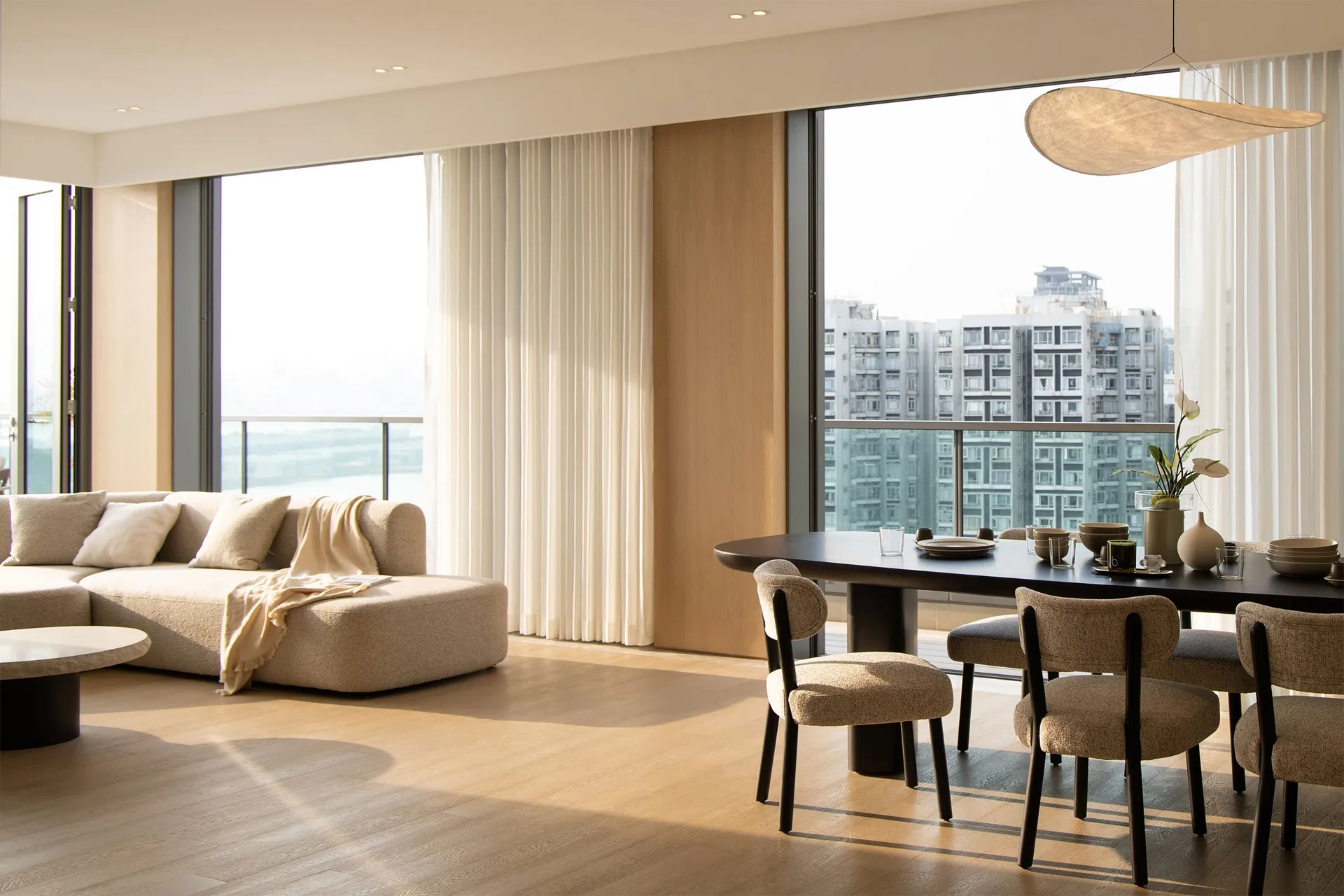 Contemporary living and dining area with wooden flooring and large windows.