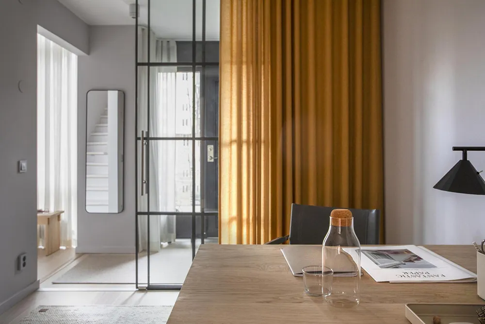 A modern office workspace featuring wooden furniture and a yellow curtain.
