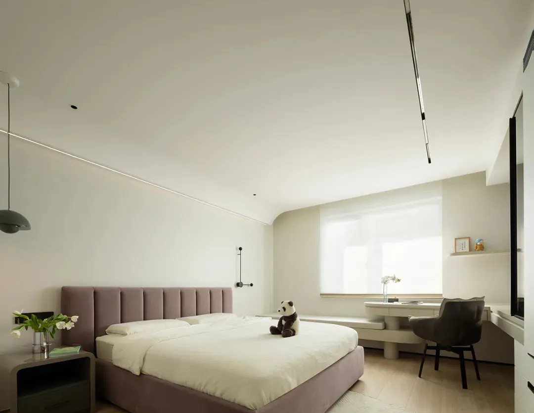 A modern white bedroom with a plush bed, decorative plant, and minimalist design.