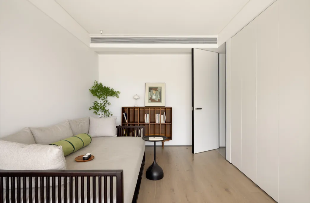 A modern minimalist living room featuring a comfortable sofa, a wooden coffee table, and a sleek metal bookshelf.