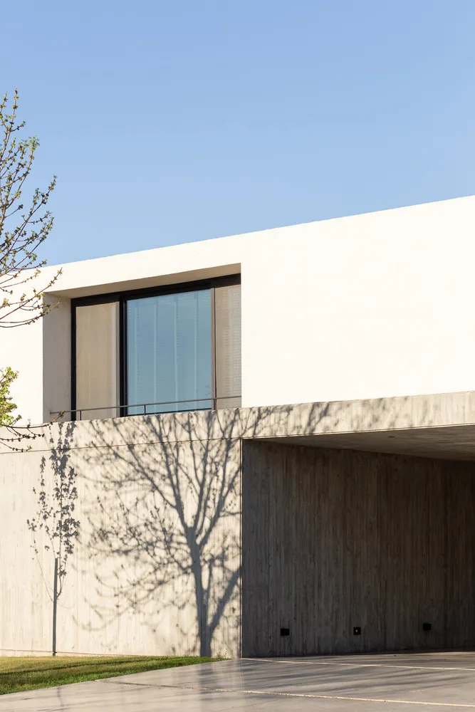 Modern minimalist building exterior with concrete walls and large glass window.