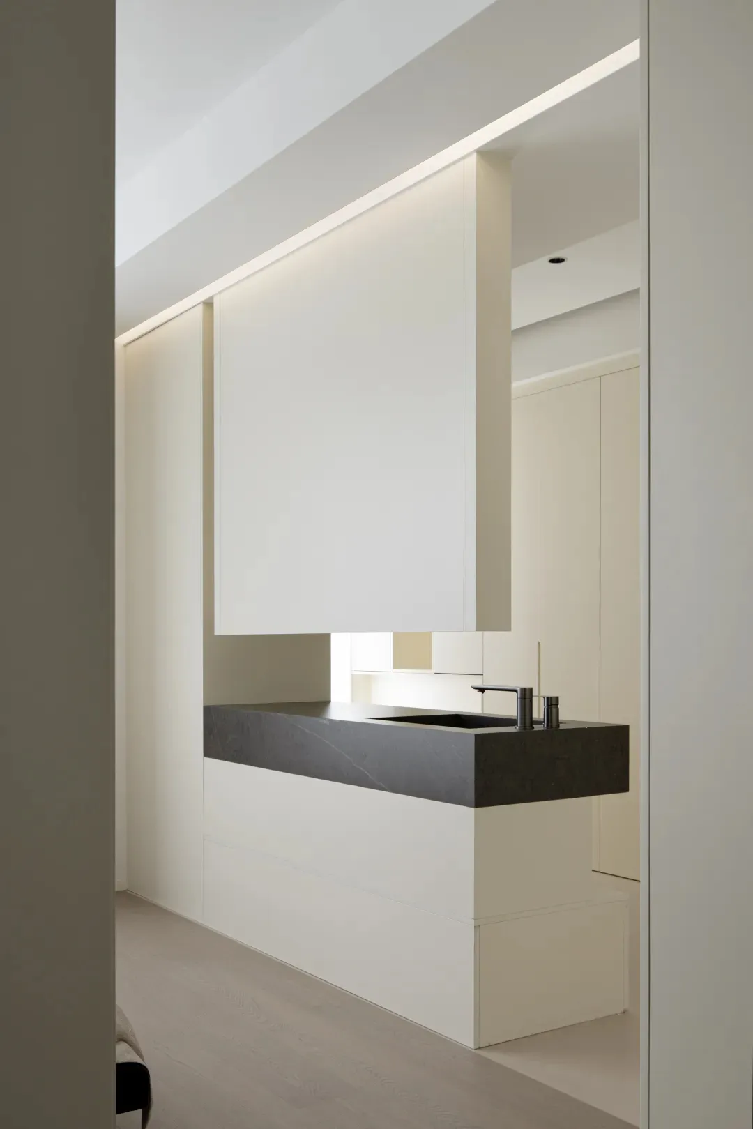 A modern kitchen with minimalist design featuring black concrete countertops and wooden cabinets.