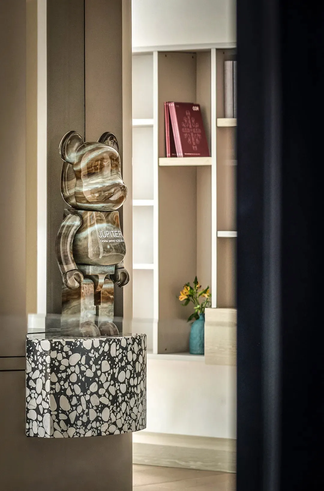 Modern interior design featuring a glass bear sculpture with the word 'Jupiter' and an orb pattern base.