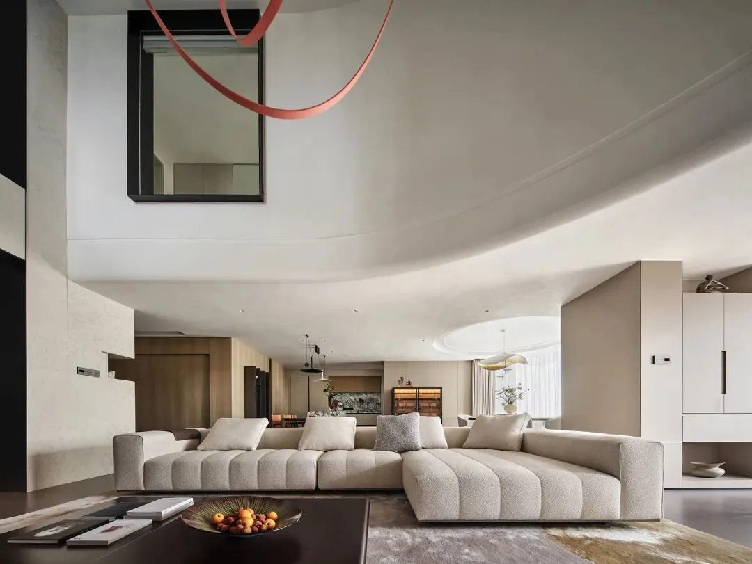 Modern living room with a large beige sectional sofa, a dark wooden dining table, and a sleek, minimalist design featuring so