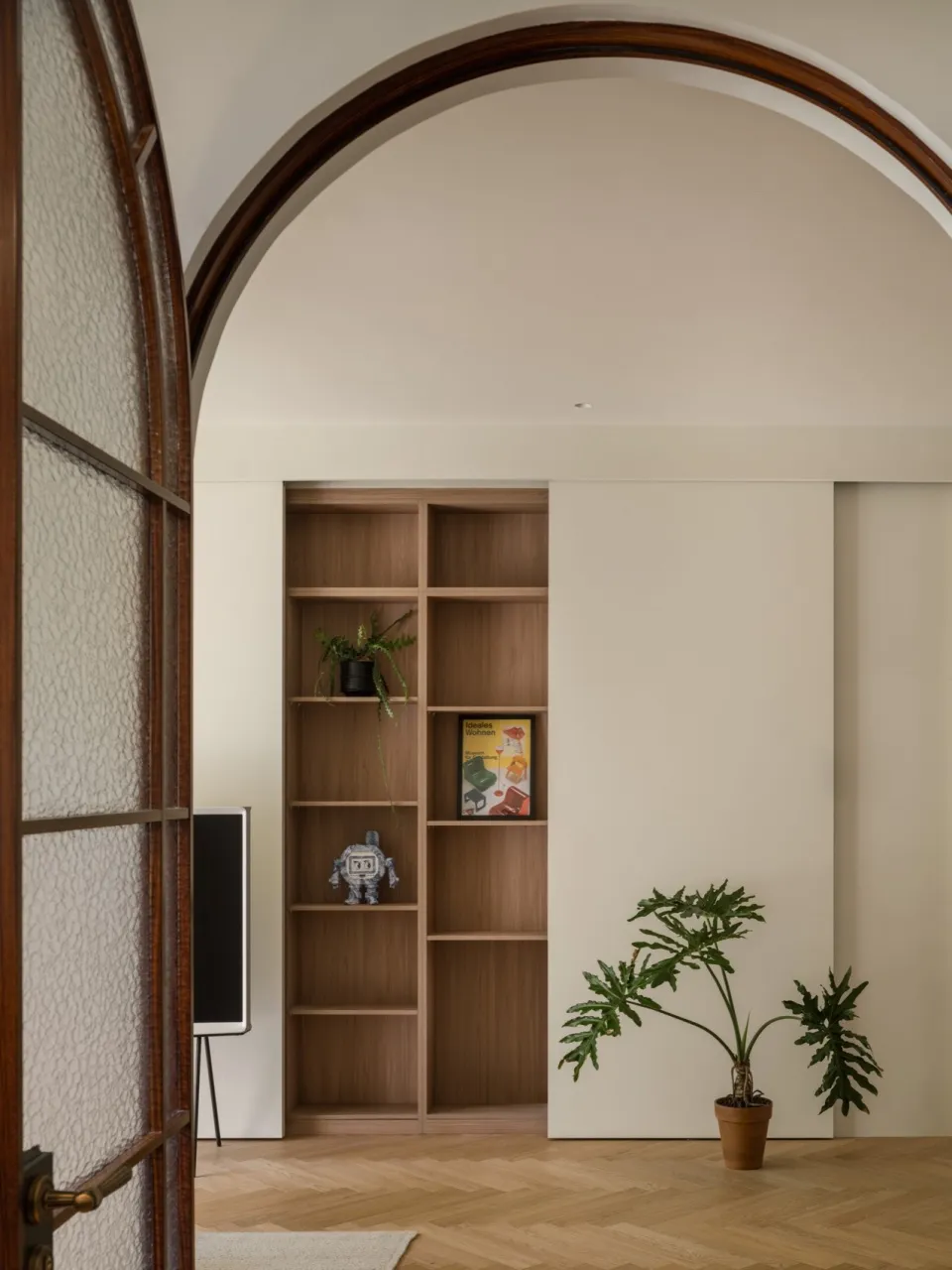 A modern interior design featuring a wooden bookshelf with plants and decorative items.