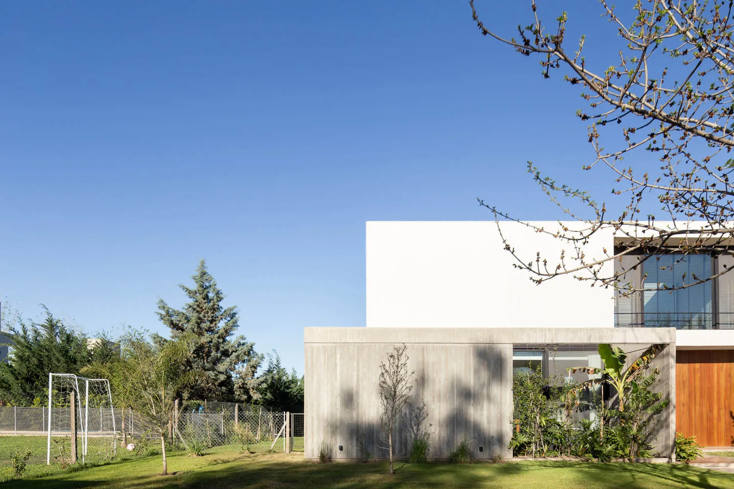 A modern residential exterior featuring a concrete walls and a landscaped yard.