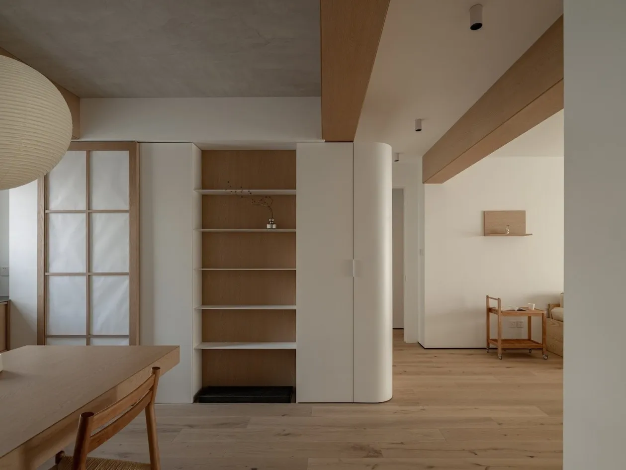 A minimalist apartment featuring a wooden interior with white finishes and natural light.