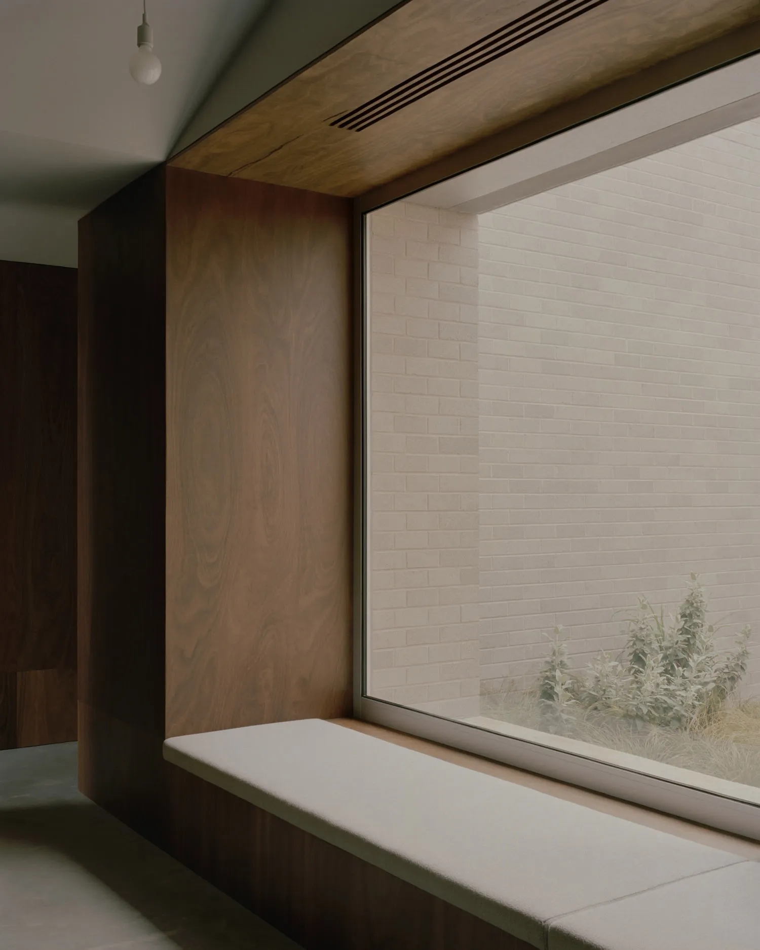 A minimalist residential interior featuring a modern window seat made of wood.