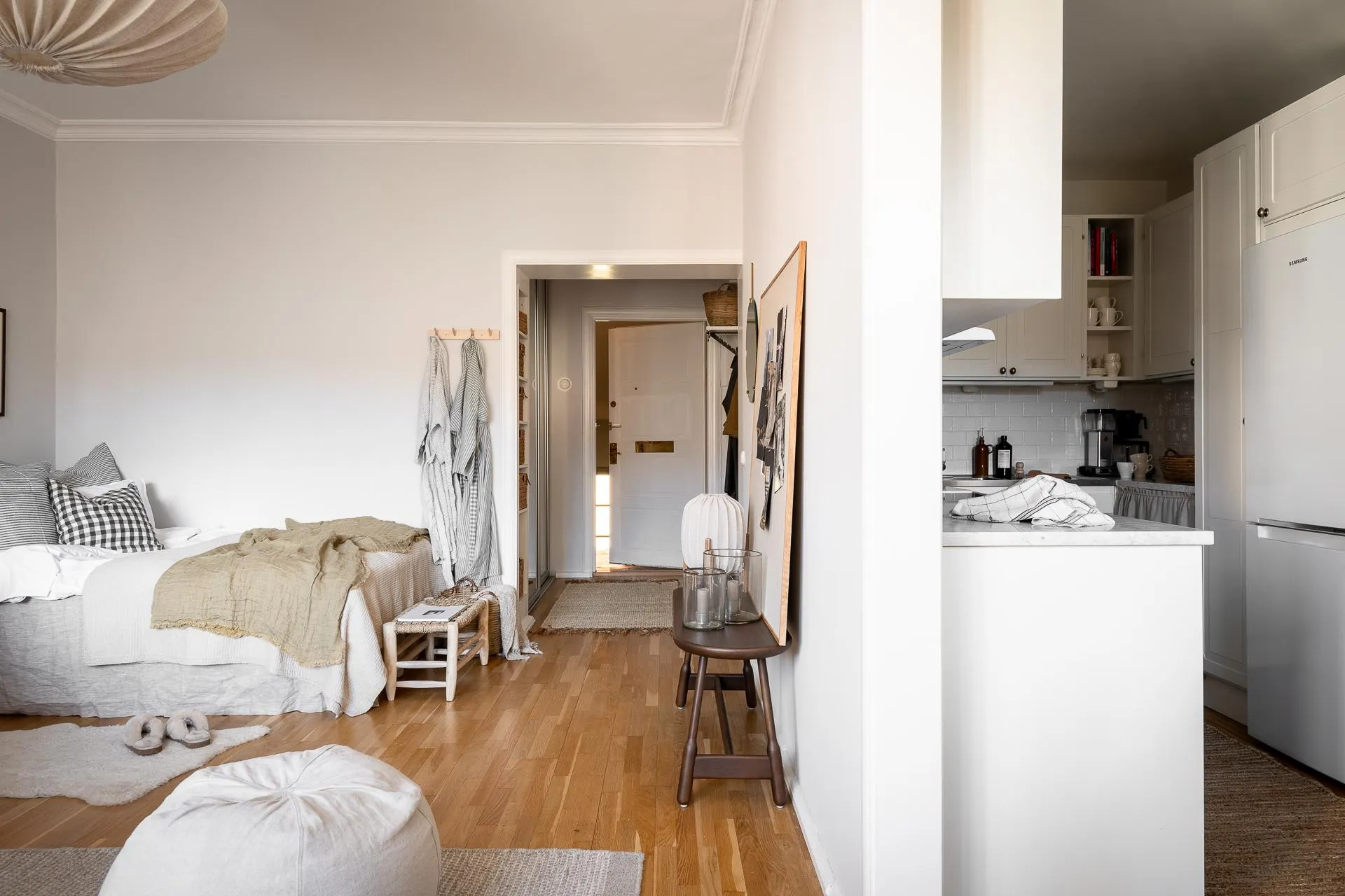 A minimalist residential space featuring white walls, wood flooring, and natural fiber textiles.