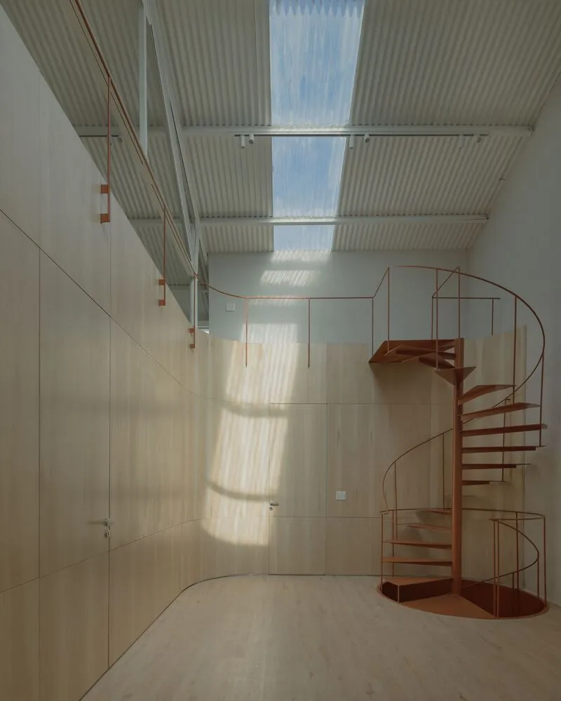Modern minimalist interior design featuring a metal spiral staircase and wooden walls.