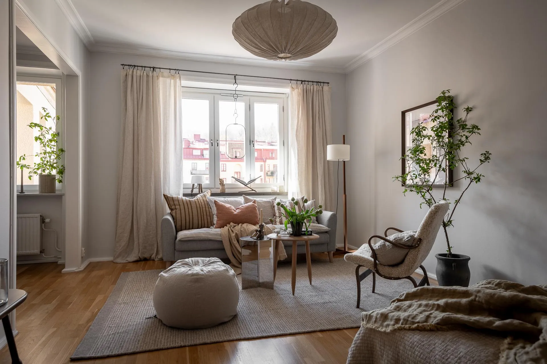 A minimalist living room with a grey sofa, wooden coffee table, and large windows.