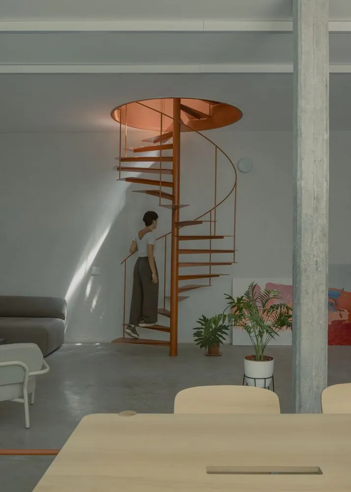 A woman walking down a modern industrial spiral staircase made of metal.