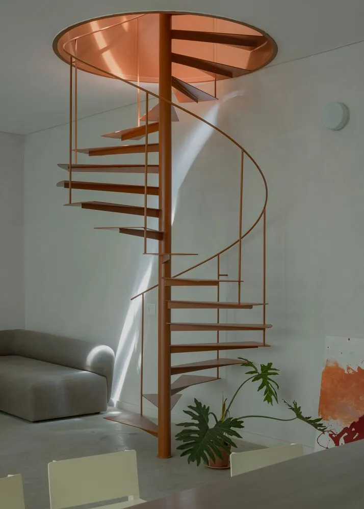 Modern interior design featuring a metal spiral staircase with a glass rail