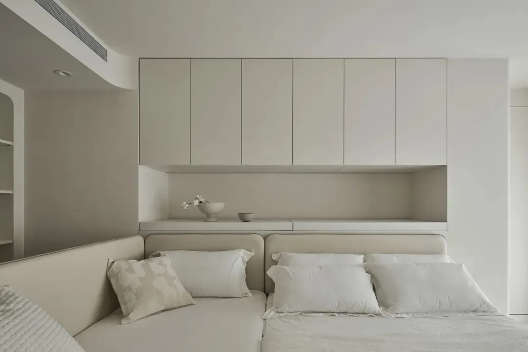 Minimalist bedroom with concrete and wood finishes, featuring a sleek bed and floating shelves.