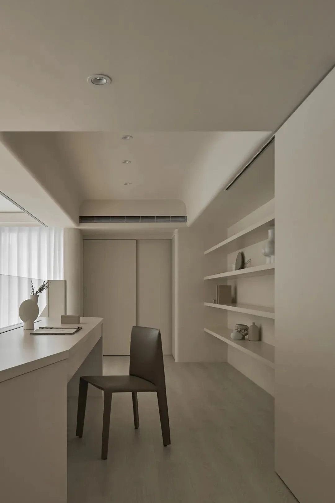 A minimalist office space with a desk, chair, and shelves