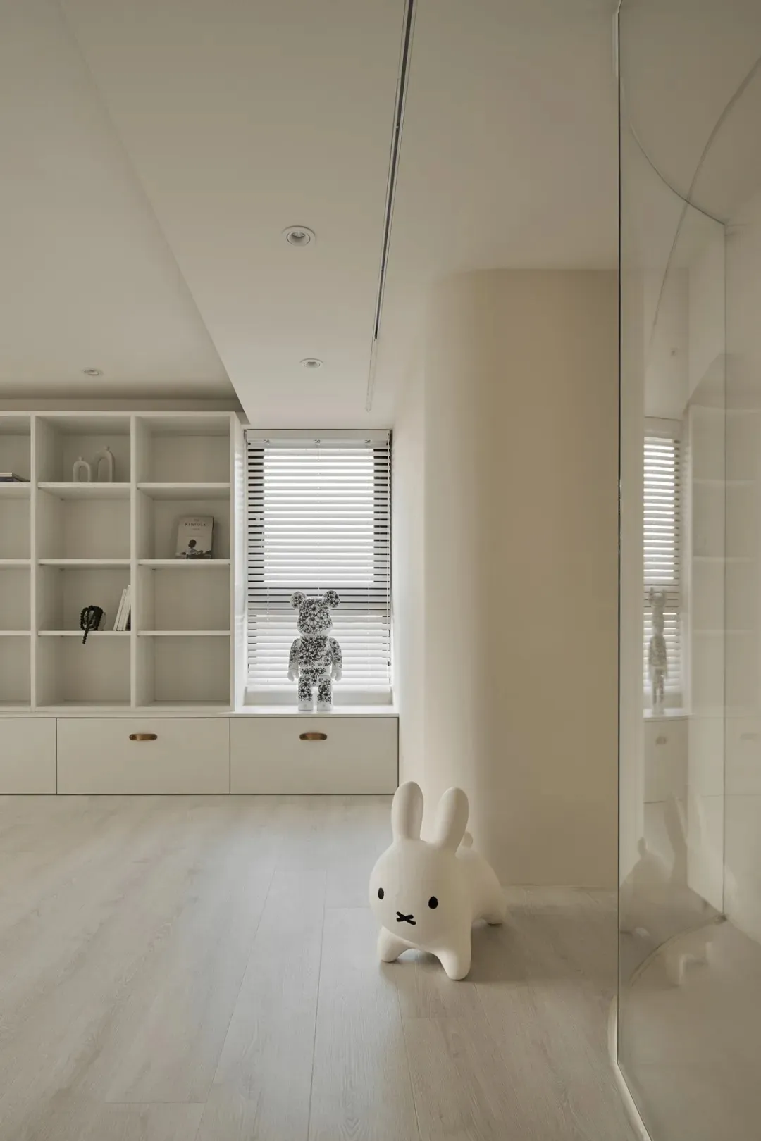 A minimalist playroom with neutral-colored walls, wooden floors, and a white rabbit figure.