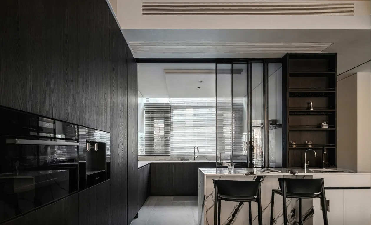 Modern kitchen with dark wood cabinets, marble countertops, and black stools.