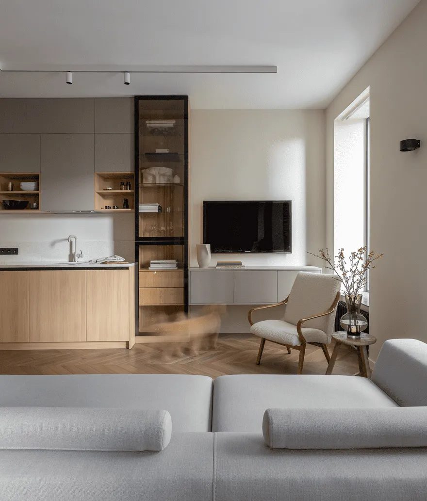 A modern living, dining, and bedroom area featuring light wood furniture, a sleek kitchen area with a flat-screen TV and a co