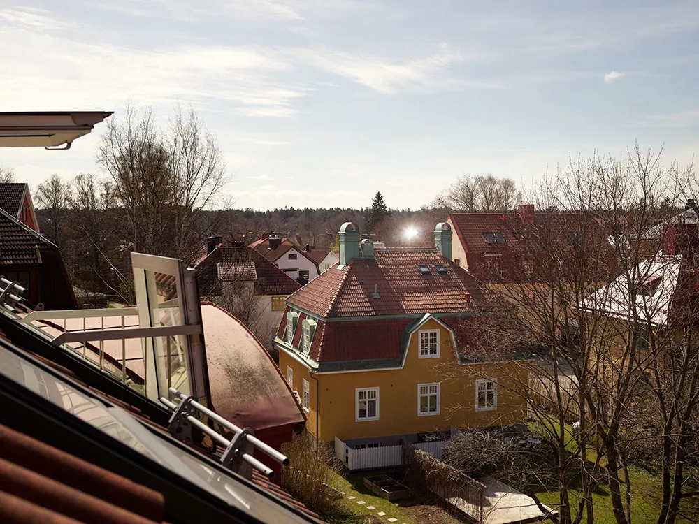 A bird's-eye view of residential houses with brick exteriors and tall trees in the background.