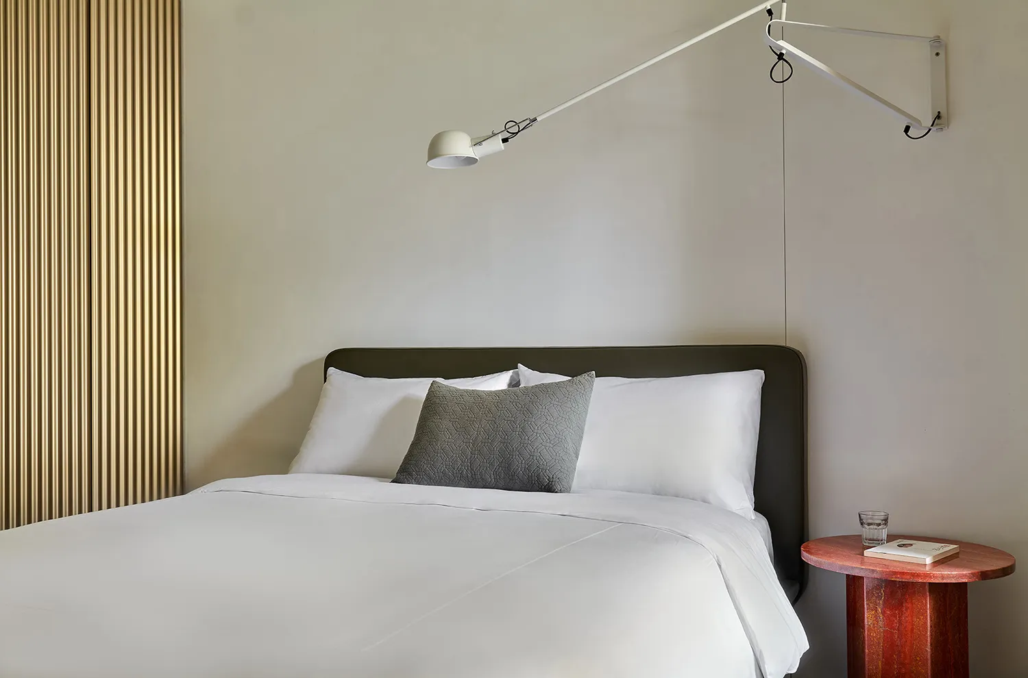 A minimalist bedroom featuring a white bed with a single decorative pillow.