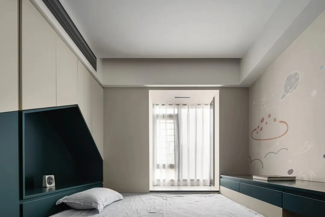 A modern children's bedroom with white walls, a single bed, and a space-themed wall mural featuring planets and clouds.