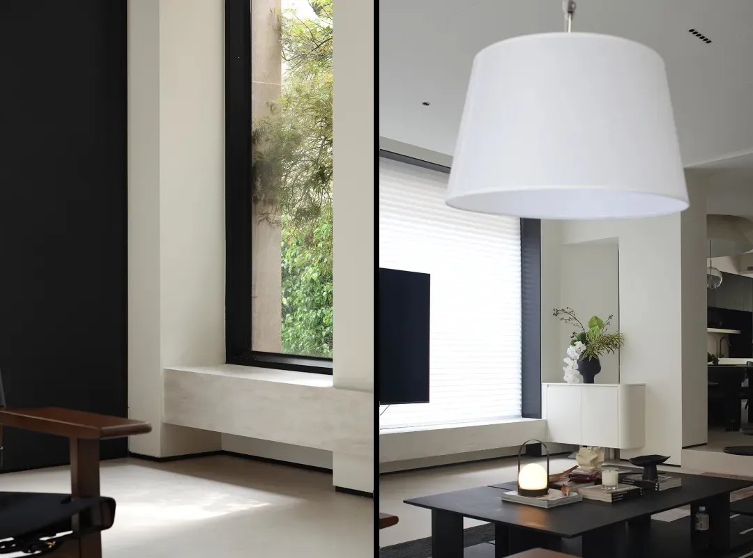 A modern living room with a minimalist white couch, a black coffee table, and large windows allowing natural light to flood t