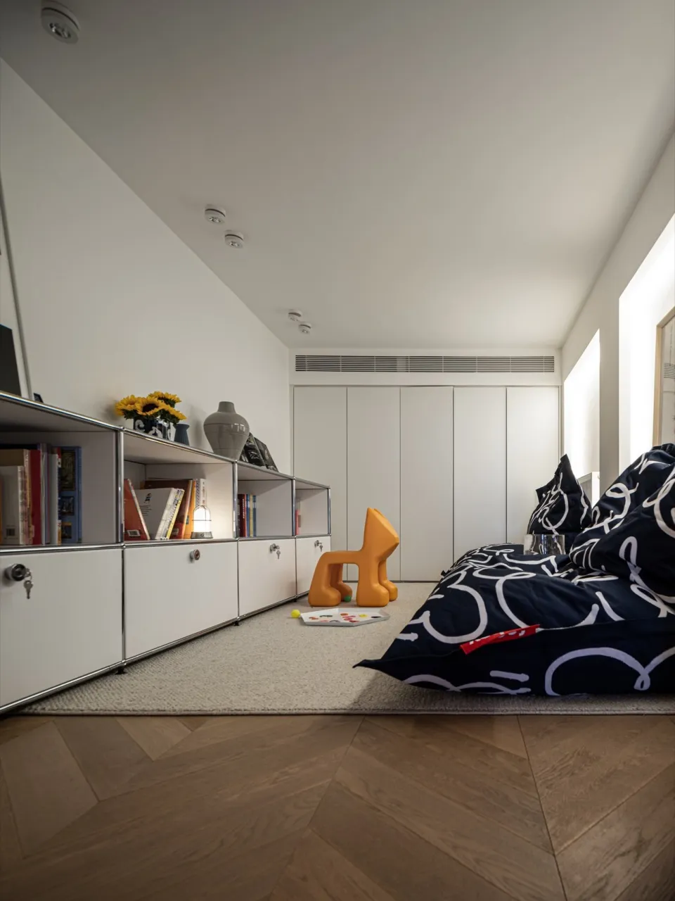 A modern living room with minimalist white furniture and wood flooring.