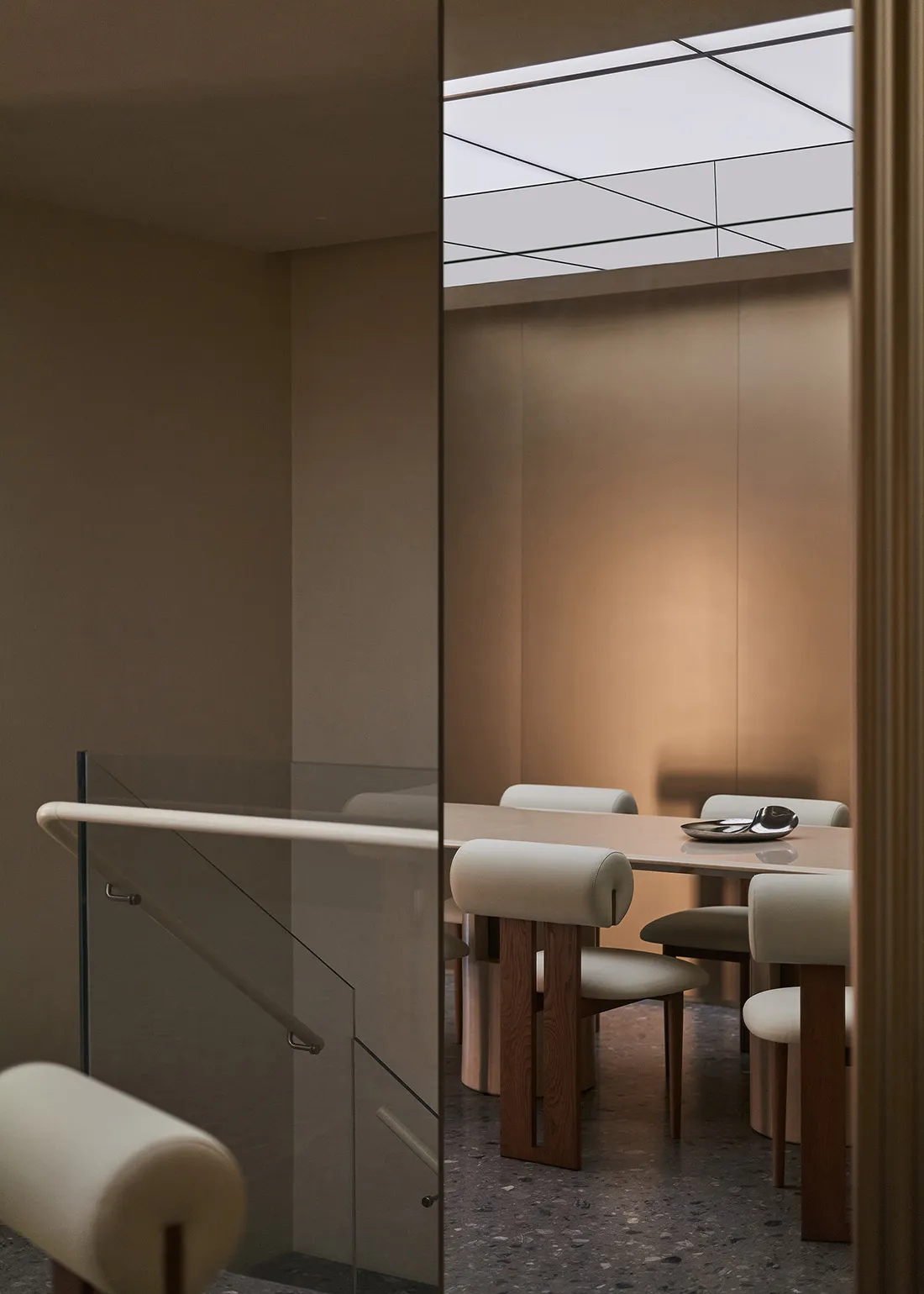 Modern minimalist dining room with wooden furniture and a glass wall.