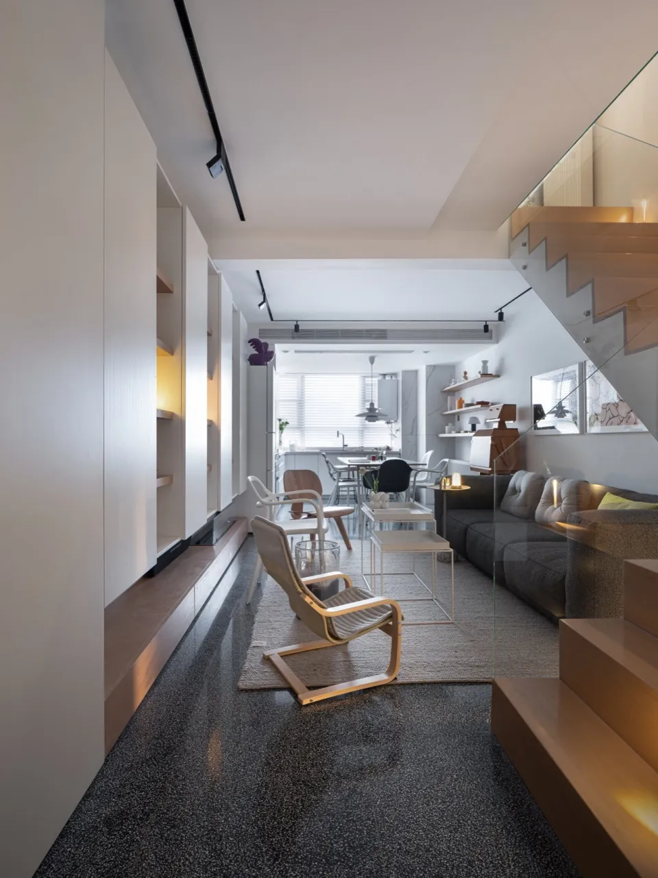 Modern minimalist living room with open shelving, wood furniture, and neutral color palette