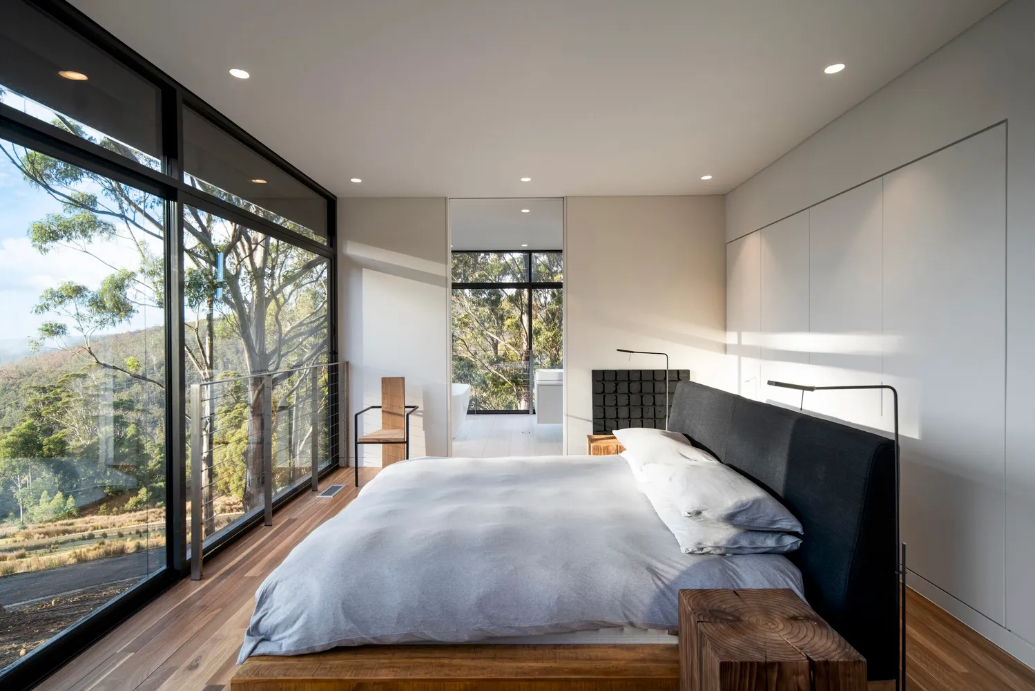 Modern bedroom with black accents, wood, and glass elements.