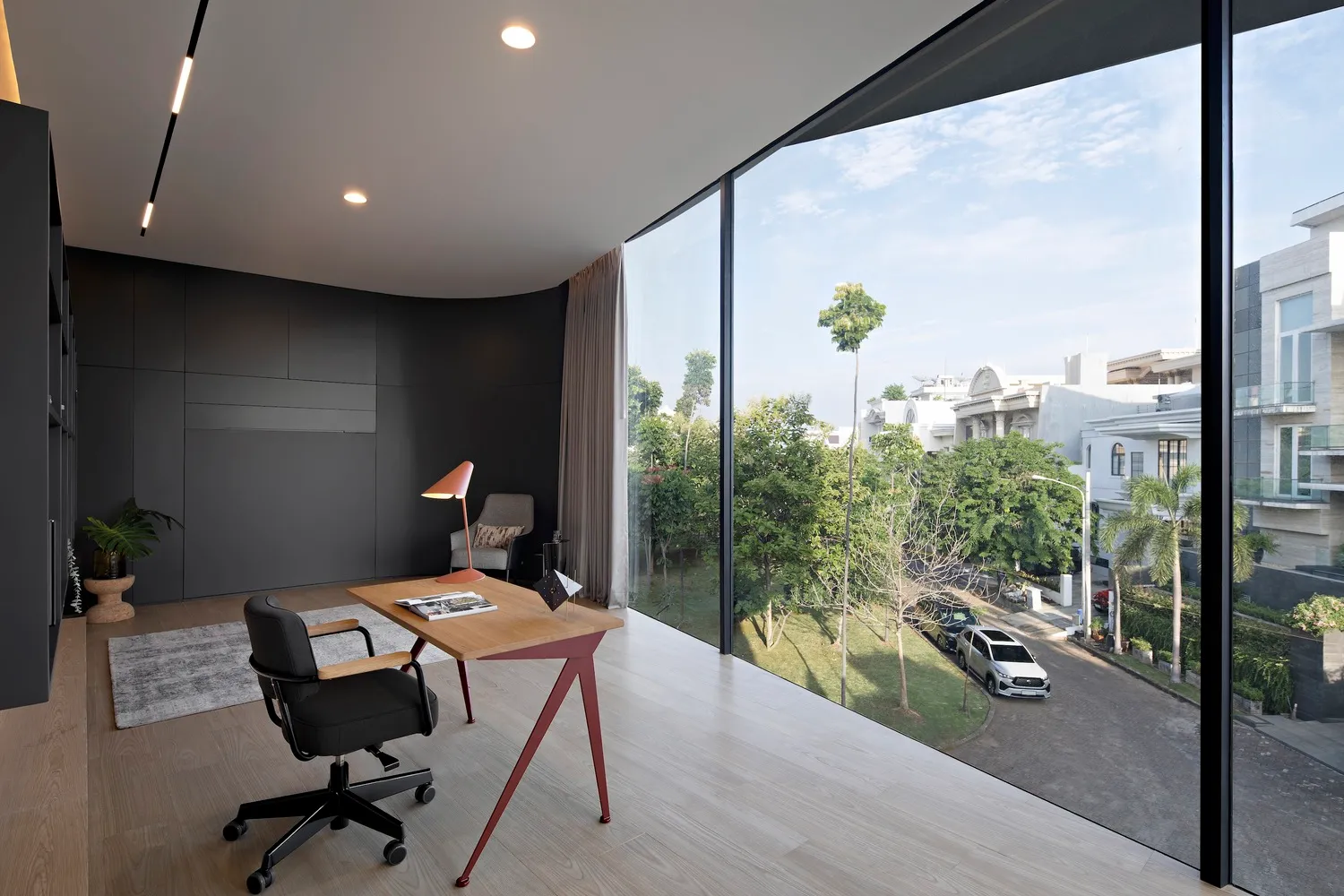 Modern home office with a glass wall overlooking a residential street