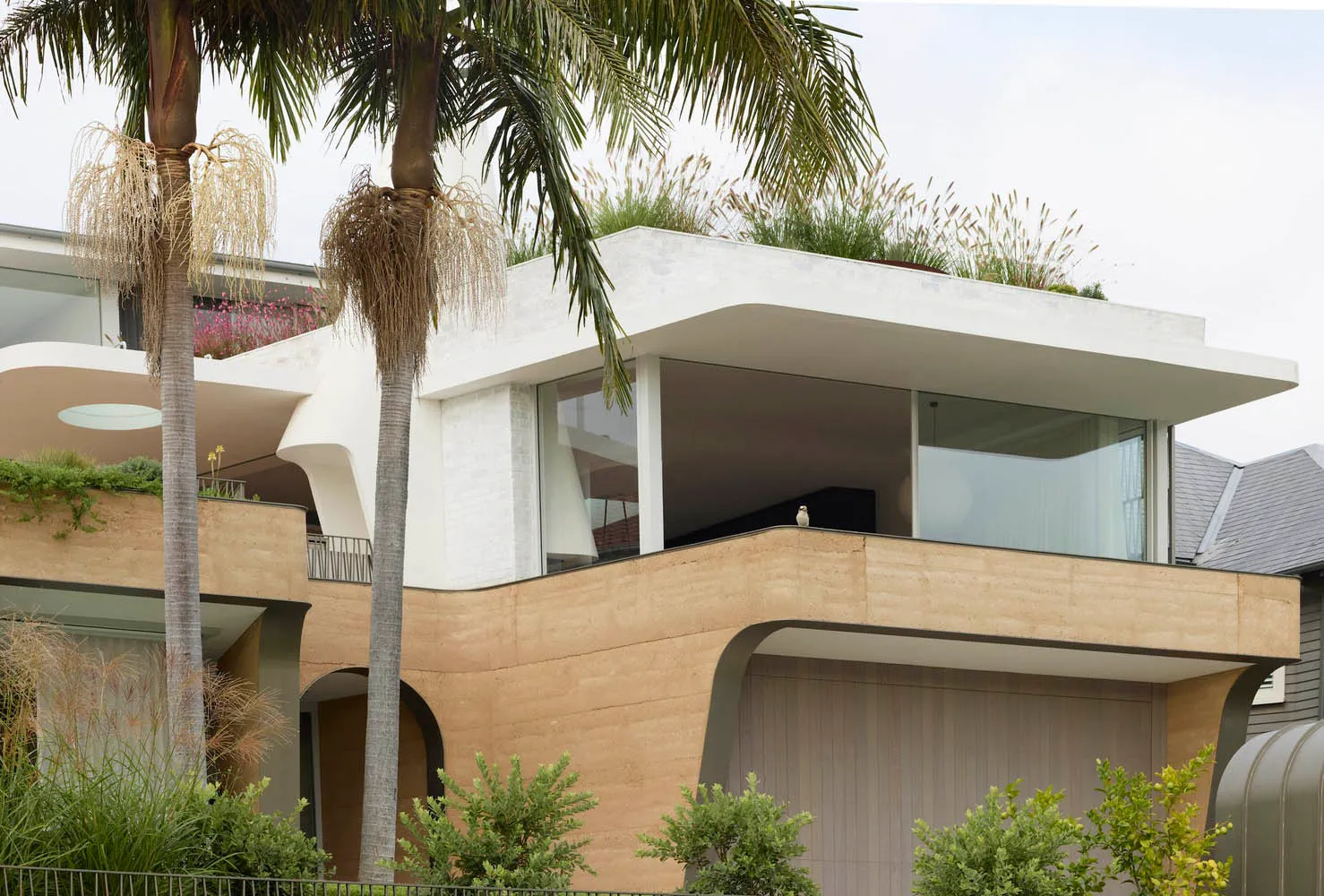 A modern house exterior featuring concrete materials and lush greenery.