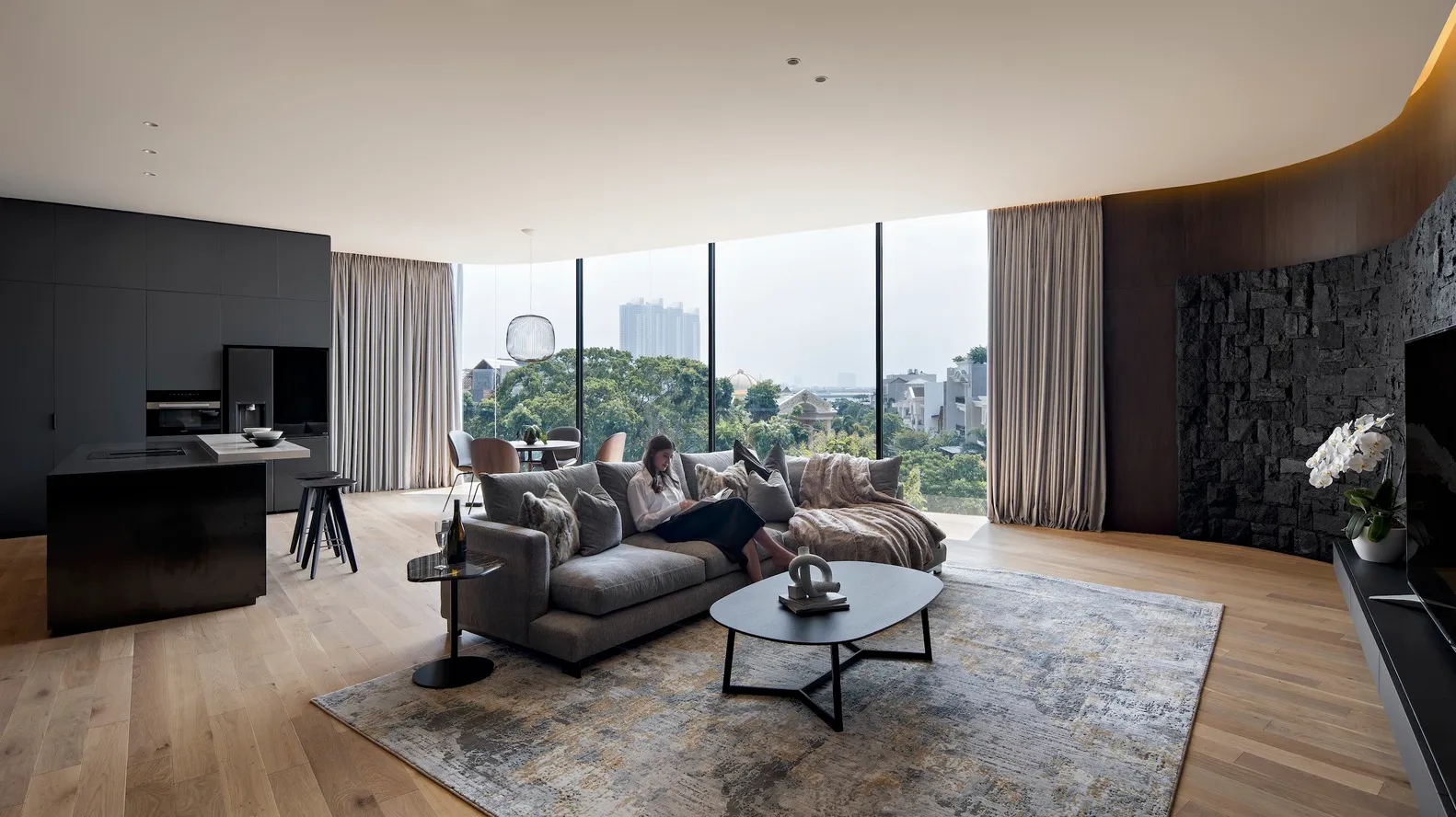 A modern living room featuring wood flooring, leather furniture, and glass walls.