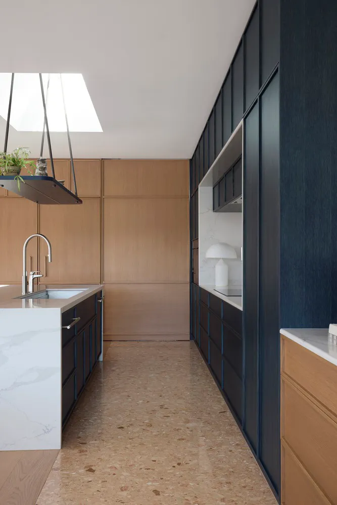 Modern minimalist kitchen featuring a sleek island with marble countertop and wooden cabinets.