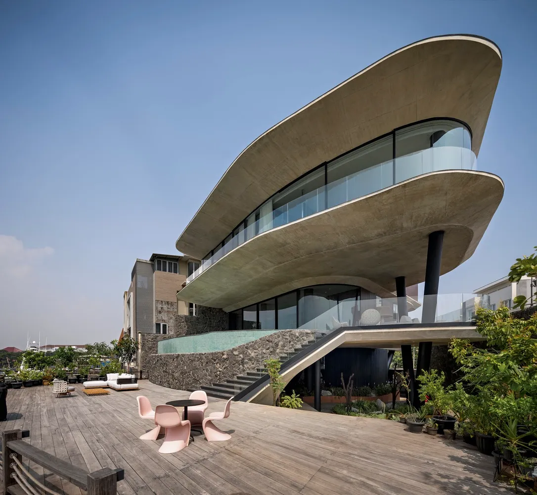 A modern residential building with a curved concrete facade and a large balcony.