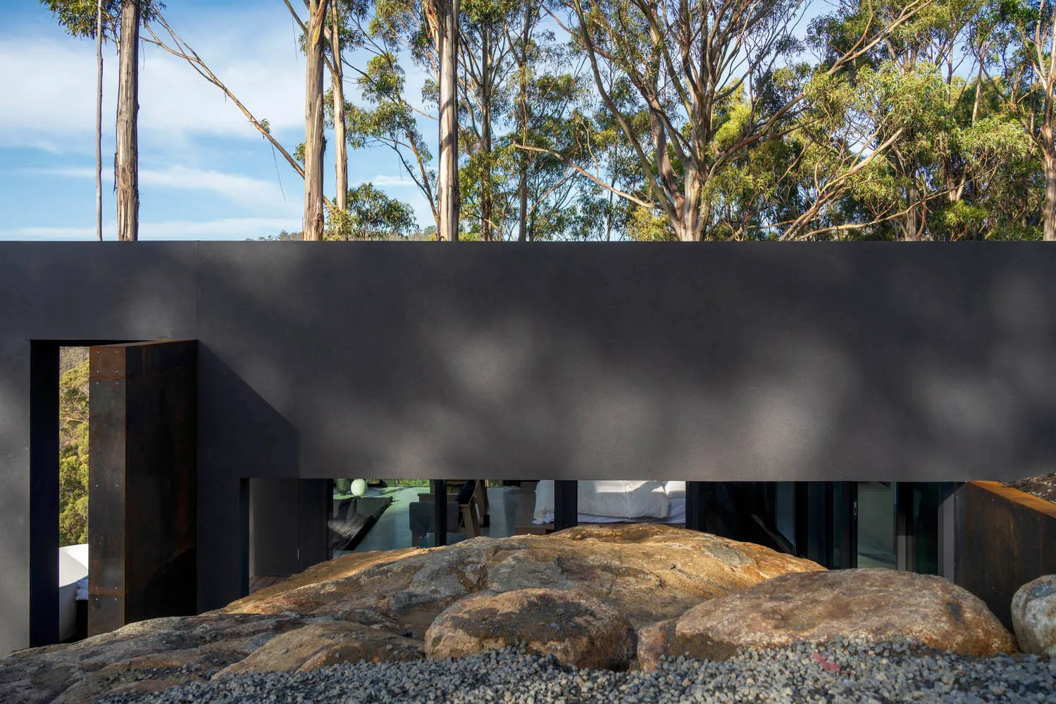 A minimalist residential house with concrete walls, surrounded by nature.